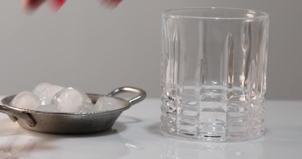 A male hand throws ice into a glass for whiskey or brandy — Stock Video