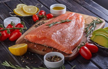 Çiğ somon fileto biber, limon biberiyesi ve kiraz domatesleri koyu ahşap bir masada. Yan görüş. Boşluğu kopyala