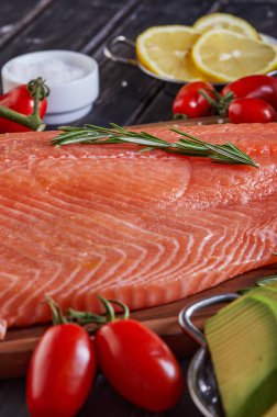 Çiğ somon fileto biber, limon biberiyesi ve kiraz domatesleri koyu ahşap bir masada. Yan görüş. Yakın plan..