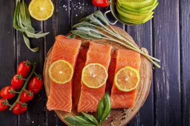 Çiğ somon filetosu dilimlenmiş, biberli limon biberiyesi ve ahşap bir masada kiraz domatesleri. Düz yatıyordu. Boşluğu kopyala