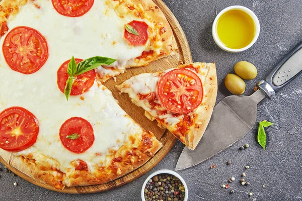 Siyah beton arka planda yemek pişirmek için İtalyan pizzası ve malzemeleri. Domates, zeytin, fesleğen ve baharat. Dilimlenmiş pizza üçgeni. Metin için alanı kopyala.