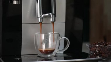 Kahve makinesinden şeffaf bir fincana kahve doldurup espresso yapmak.