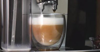 Kahve makinesiyle şeffaf bir fincanda cappuccino kahvesi yapmak.