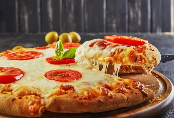 The delicious taste of pizza and slices of cheese with mozzarella and tomatoes. Triangle pizza with stretching cheese and spices. Copy space for text.