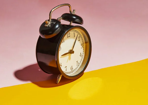 Schwarzer Wecker Mit Hartem Schatten Auf Rosa Gelbem Hintergrund — Stockfoto