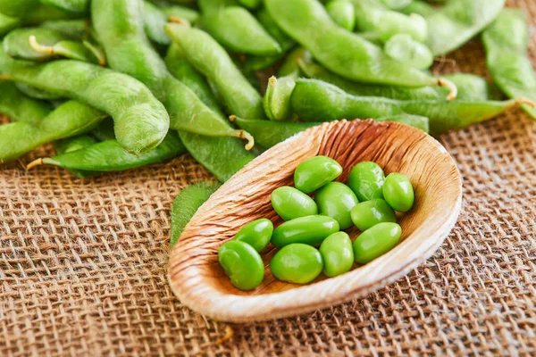 Kahverengi bir çuval bezi üzerinde ahşap bir tabakta soya fasulyesi ya da edamame.