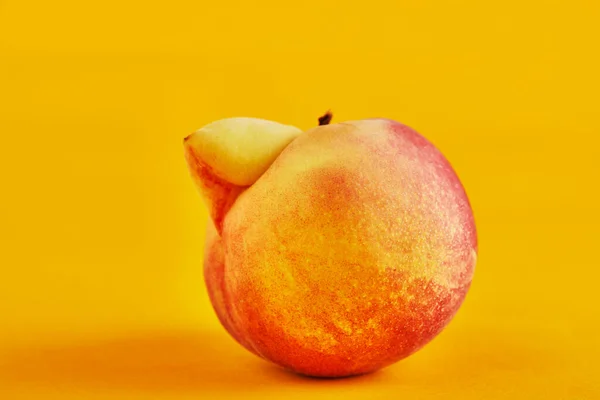 Ein hässliches Obst oder Gemüse. Sehr hässliche Pfirsich-Mutation auf orangefarbenem Hintergrund. Hässliches Obst ist nicht gefragt — Stockfoto