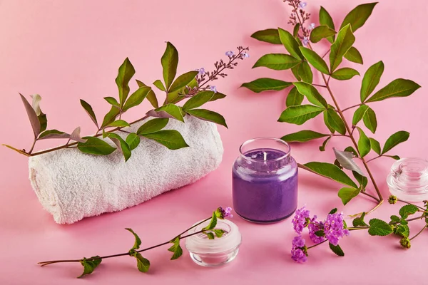 Scented candle for Spa and home with lavender scent and green leaves on a pink background.