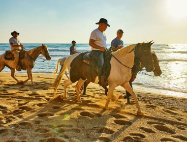 Arsuf, İsrail - 22 Temmuz 2020: Akdeniz kıyısı boyunca gün batımında at sürmek.