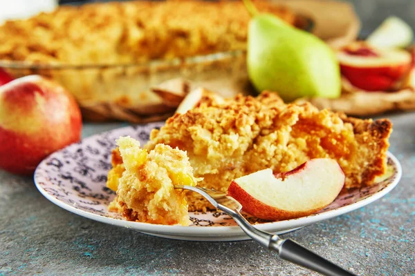 A slice of peach and pear pie on a plate and a piece chopped onto a fork.