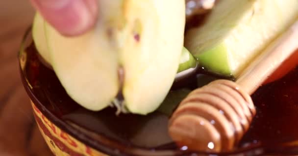 Trempette une pomme dans du miel dans un bol sur un stand en bois, Rosh hashanah concept de vacances du Nouvel An juif. — Video