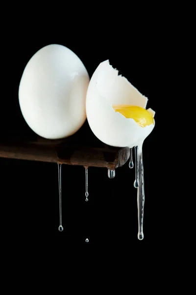 一只蛋被打破 蛋黄可见 白色在黑色的背景上流下来 — 图库照片