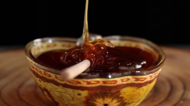 Bal ince bir derede sopayla elma şeklindeki bir kaseye dökülür, Rosh hashanah - Yahudi Yeni Yıl tatili konsepti.