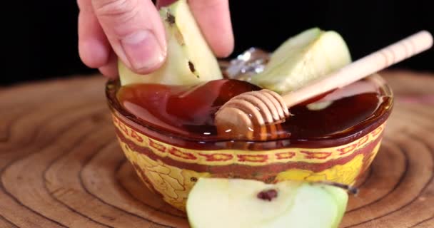 Погружает яблоко в мед в миску на деревянном стенде, Рош ха-Шана - еврейская новогодняя праздничная концепция — стоковое видео
