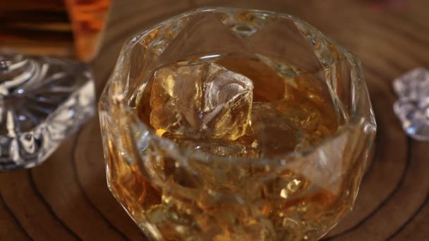 Налить виски в стакан со льдом в замедленной съемке — стоковое видео