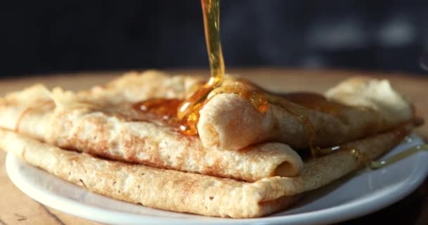 Pancake di atas piring yang dituangkan dengan madu dari tongkat kayu — Stok Video