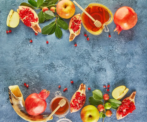 Rosh hashanah - Yahudi Yeni Yıl tatili konsepti. Geleneksel semboller: Bal kavanozu ve narlı taze elmalar ve mavi arka planda shofar boynuzu. Uzayı metin için kopyala. Yukarıdan görüntüle.