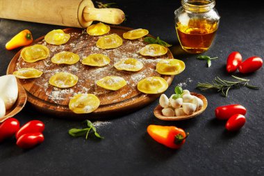 Unlu çiğ ravioli, kiraz domatesleri, ayçiçeği yağı ve koyu arkaplanda fesleğen. İtalyan mantısı yapma süreci. Yan görünüm.