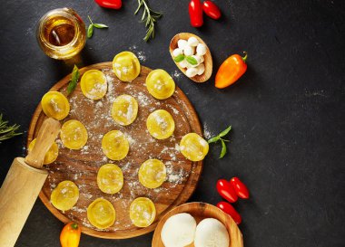 Unlu çiğ ravioli, kiraz domatesleri, ayçiçeği yağı ve koyu arkaplanda fesleğen. İtalyan mantısı yapma süreci. Uzayı kopyala Düz yatıyordu