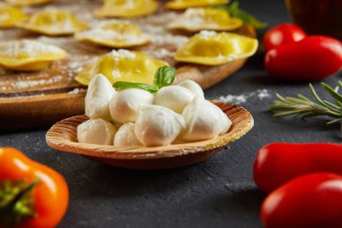 Unlu çiğ ravioli, kiraz domatesleri, ayçiçeği yağı ve koyu arkaplanda fesleğen. İtalyan mantısı yapma süreci. Yan görünüm.