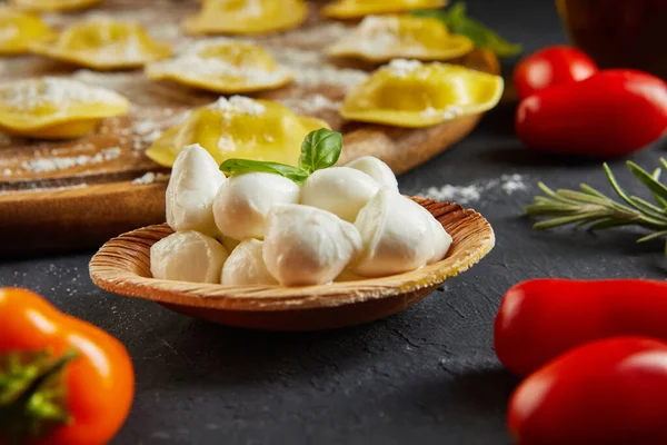 Unlu çiğ ravioli, kiraz domatesleri, ayçiçeği yağı ve koyu arkaplanda fesleğen. İtalyan mantısı yapma süreci. Yan görünüm.