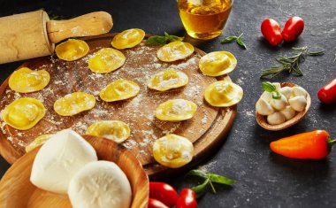 Unlu çiğ ravioli, kiraz domatesleri, ayçiçeği yağı ve koyu arkaplanda fesleğen. İtalyan mantısı yapma süreci. Yan görünüm.