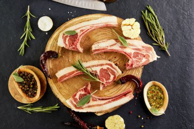 Pişirmek için malzemeli çiğ kuzu kaburga: ahşap tezgahta tuz, biber, zeytinyağı ve otlar. Düz yatıyordu