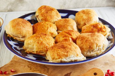 Asya usulü etli turtalar - samsa ya da sambousak ulusal tabakta nar, Orta Doğu mutfağı ve ahşap beyaz bir masa. Kapat.