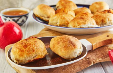 Asya usulü etli turtalar - samsa ya da sambousak ulusal tabakta nar ve bir kâsede çay, ahşap beyaz bir masada Orta Doğu mutfağı.