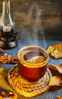 Sonbahar, sonbahar yaprakları, sıcak bir fincan kahve ve mavi bir masanın arka planında sıcak bir eşarp. Mevsimlik, sabah kahvesi, pazar rahatlaması ve durgun hayat konsepti..