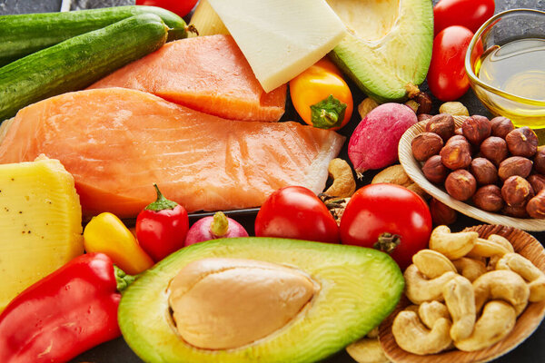 Ketogenic diet concept. Low carb keto diet food set. Green vegetables, nuts, fish fillets, cherry tomatoes. Healthy food concept.