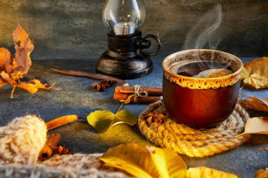 Sonbahar, sonbahar yaprakları, sıcak bir fincan kahve ve mavi bir masanın arka planında sıcak bir eşarp. Mevsimlik, sabah kahvesi, pazar rahatlaması ve durgun hayat konsepti..