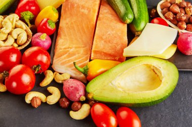 Ketogenik diyet konsepti. Düşük karbonhidratlı diyet yemek seti. Yeşil sebze, fındık, balık filetosu, vişneli domates. Sağlıklı gıda konsepti.