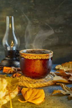 Sonbahar, sonbahar yaprakları, sıcak bir fincan kahve ve mavi bir masanın arka planında sıcak bir eşarp. Mevsimlik, sabah kahvesi, pazar rahatlaması ve durgun hayat konsepti..