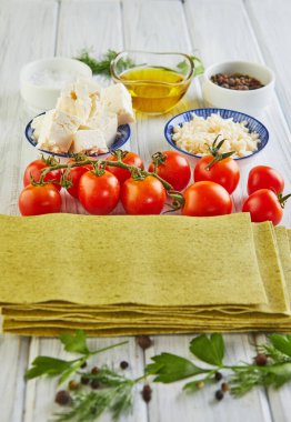 Ispanaklı lazanya pişirmek için çarşaflar, domates, peynir, tereyağı, biber ve şifalı bitkiler. Yemek çırpma.