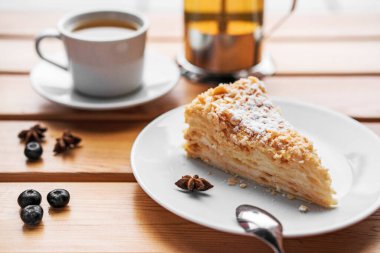 Ahşap masada meyveli katmanlı kek ve kapuçino..