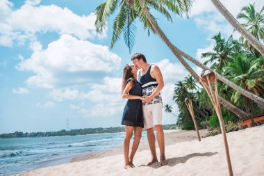 Güzel bir tropikal plaja seyahatte sevgi dolu bir erkekle bir kadını öpmek. Palmiye ağaçları, güneş ve kum. Tropik ada plajı ve okyanusu.