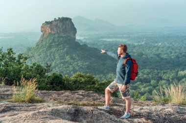Sırt çantalı genç adam Sri Lanka 'daki Pidurangala Rock' tan Sigirya Rock View 'a karşı.