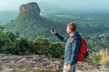 Sırt çantalı genç adam Sri Lanka 'daki Pidurangala Rock' tan Sigirya Rock View 'a karşı.