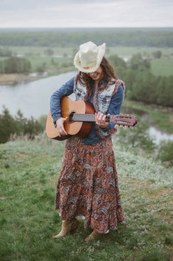 Voronezh, Rusya, Mayıs 2017. Kıyafet tarzı 2017. Özgürlük ve gençlik yaşam tarzı kavramı. Etekli, desenli, kot gömlekli ve gitarlı bir kız. Sadece editör kullanımı