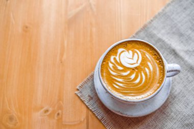 Süt köpüğünde güzel desenli kapuçino bardakları. Yazı için yeri olan ahşap masa. Yukarıdan görünüşü