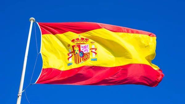 Spaanse vlag op een blauwe hemel — Stockfoto