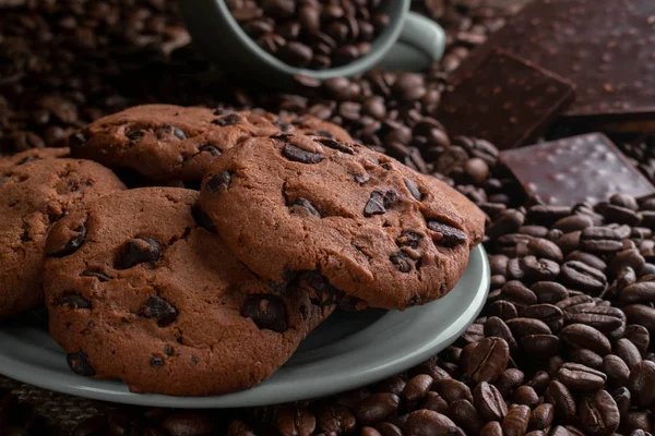 Coffee beans with chocolate and cookies in a cup and a plate — Stock Photo, Image