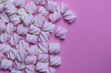 Birçok marshmallow pembe bir arka plan üzerinde solda serilir.