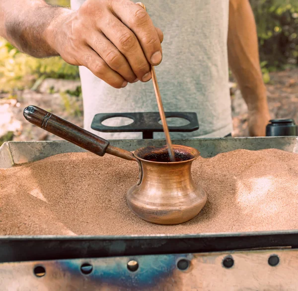 The process of making Turkish coffee on hot sand in a Turk. With — Stock Photo, Image
