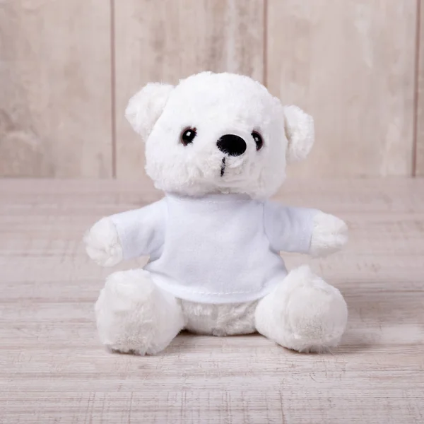 Niedlicher Teddybär sitzt auf altem Holzhintergrund — Stockfoto