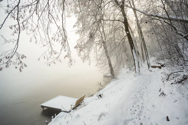 在雾中冰封的冬湖上的码头 — 图库照片