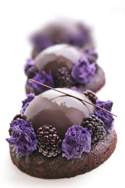 Desserts en mousse au chocolat violet avec glaçure miroir brillante, éponge micro-ondes et mûres isolées sur fond blanc — Photo