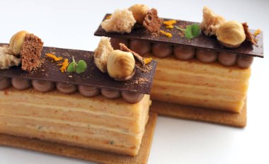 Beyaz arka plan üzerinde izole dilimlerle fındık ve ganache çerez temel iki portakal Opera pasta
