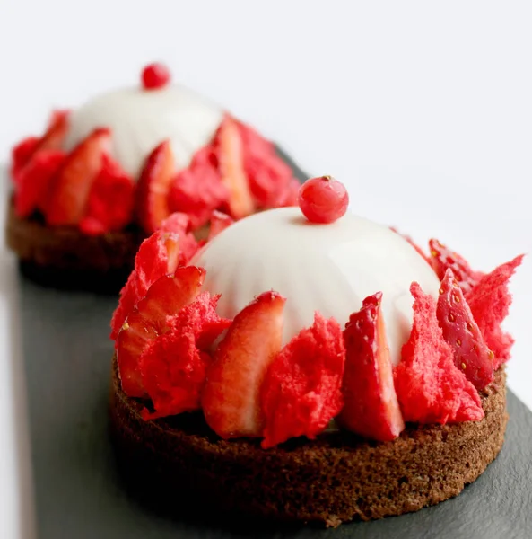 Red and white strawberry mousse desserts on brownie base with fresh berries and microwave sponge — Stock Photo, Image